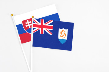 Anguilla and Slovakia stick flags on white background. High quality fabric, miniature national flag. Peaceful global concept.White floor for copy space.