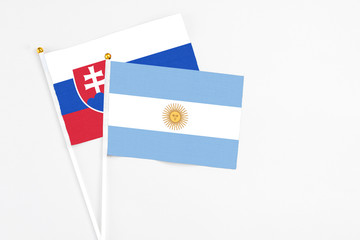 Argentina and Slovakia stick flags on white background. High quality fabric, miniature national flag. Peaceful global concept.White floor for copy space.