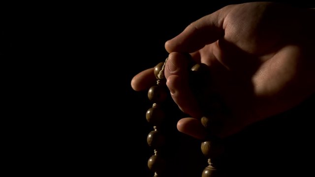 Hand with beads against black background - Eastern rosary with incense smoke