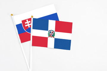 Dominican Republic and Slovakia stick flags on white background. High quality fabric, miniature national flag. Peaceful global concept.White floor for copy space.