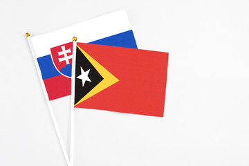 East Timor and Slovakia stick flags on white background. High quality fabric, miniature national flag. Peaceful global concept.White floor for copy space.