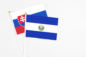 El Salvador and Slovakia stick flags on white background. High quality fabric, miniature national flag. Peaceful global concept.White floor for copy space. - obrazy, fototapety, plakaty