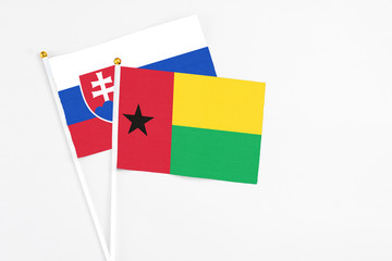 Guinea Bissau and Slovakia stick flags on white background. High quality fabric, miniature national flag. Peaceful global concept.White floor for copy space.