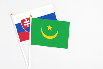 Mauritania and Slovakia stick flags on white background. High quality fabric, miniature national flag. Peaceful global concept.White floor for copy space.