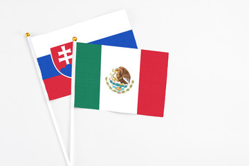 Mexico and Slovakia stick flags on white background. High quality fabric, miniature national flag. Peaceful global concept.White floor for copy space.
