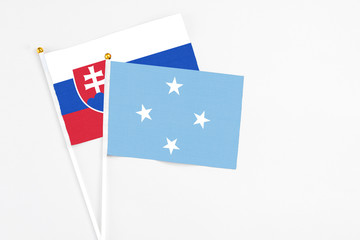 Micronesia and Slovakia stick flags on white background. High quality fabric, miniature national flag. Peaceful global concept.White floor for copy space.