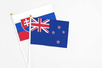 Fototapeta premium New Zealand and Slovakia stick flags on white background. High quality fabric, miniature national flag. Peaceful global concept.White floor for copy space.