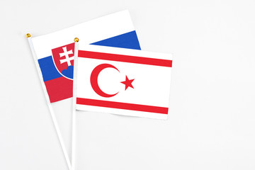 Northern Cyprus and Slovakia stick flags on white background. High quality fabric, miniature national flag. Peaceful global concept.White floor for copy space.