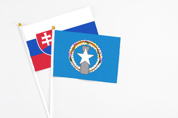 Northern Mariana Islands and Slovakia stick flags on white background. High quality fabric, miniature national flag. Peaceful global concept.White floor for copy space.