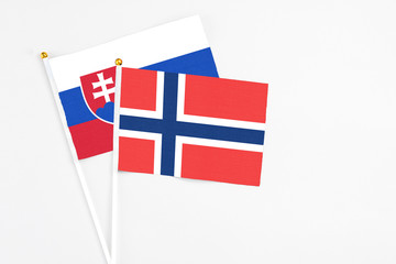 Norway and Slovakia stick flags on white background. High quality fabric, miniature national flag. Peaceful global concept.White floor for copy space.