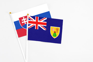 Fototapeta premium Turks And Caicos Islands and Slovakia stick flags on white background. High quality fabric, miniature national flag. Peaceful global concept.White floor for copy space.