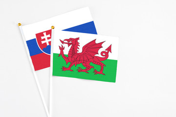 Wales and Slovakia stick flags on white background. High quality fabric, miniature national flag. Peaceful global concept.White floor for copy space.