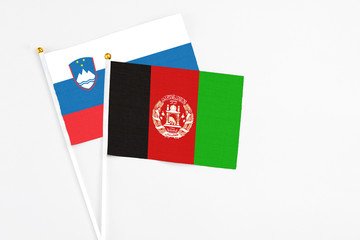 Afghanistan and Slovenia stick flags on white background. High quality fabric, miniature national flag. Peaceful global concept.White floor for copy space.
