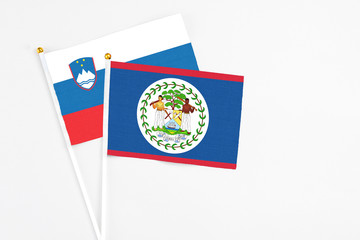 Belize and Slovenia stick flags on white background. High quality fabric, miniature national flag. Peaceful global concept.White floor for copy space.