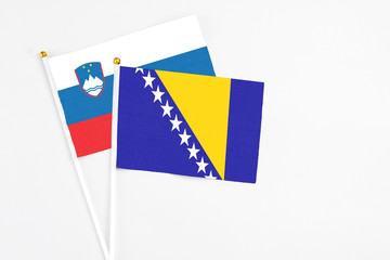 Bosnia Herzegovina and Slovenia stick flags on white background. High quality fabric, miniature national flag. Peaceful global concept.White floor for copy space.