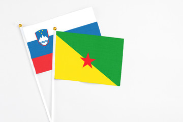 French Guiana and Slovenia stick flags on white background. High quality fabric, miniature national flag. Peaceful global concept.White floor for copy space.