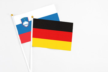 Germany and Slovenia stick flags on white background. High quality fabric, miniature national flag. Peaceful global concept.White floor for copy space.