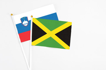 Jamaica and Slovenia stick flags on white background. High quality fabric, miniature national flag. Peaceful global concept.White floor for copy space.