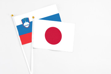 Japan and Slovenia stick flags on white background. High quality fabric, miniature national flag. Peaceful global concept.White floor for copy space.