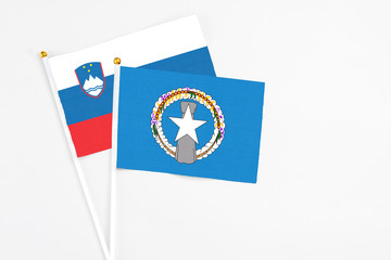 Northern Mariana Islands and Slovenia stick flags on white background. High quality fabric, miniature national flag. Peaceful global concept.White floor for copy space.