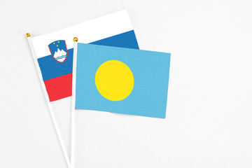 Palau and Slovenia stick flags on white background. High quality fabric, miniature national flag. Peaceful global concept.White floor for copy space.