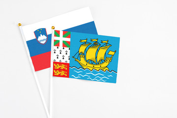 Saint Pierre And Miquelon and Slovenia stick flags on white background. High quality fabric, miniature national flag. Peaceful global concept.White floor for copy space.