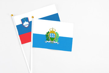 San Marino and Slovenia stick flags on white background. High quality fabric, miniature national flag. Peaceful global concept.White floor for copy space.