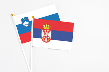 Serbia and Slovenia stick flags on white background. High quality fabric, miniature national flag. Peaceful global concept.White floor for copy space.