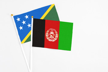 Afghanistan and Solomon Islands stick flags on white background. High quality fabric, miniature national flag. Peaceful global concept.White floor for copy space.