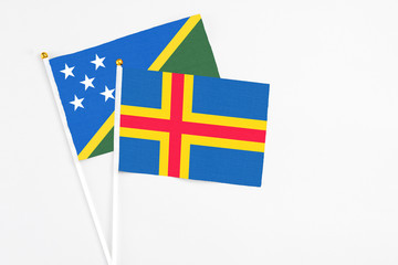 Aland Islands and Solomon Islands stick flags on white background. High quality fabric, miniature...