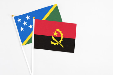Angola and Solomon Islands stick flags on white background. High quality fabric, miniature national flag. Peaceful global concept.White floor for copy space.