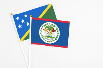 Belize and Solomon Islands stick flags on white background. High quality fabric, miniature national flag. Peaceful global concept.White floor for copy space.