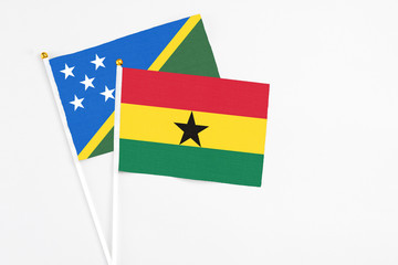 Ghana and Solomon Islands stick flags on white background. High quality fabric, miniature national flag. Peaceful global concept.White floor for copy space.