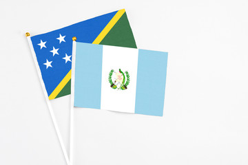 Guatemala and Solomon Islands stick flags on white background. High quality fabric, miniature national flag. Peaceful global concept.White floor for copy space.