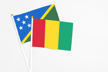 Guinea and Solomon Islands stick flags on white background. High quality fabric, miniature national flag. Peaceful global concept.White floor for copy space.