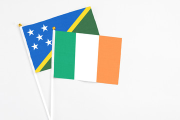 Ireland and Solomon Islands stick flags on white background. High quality fabric, miniature national flag. Peaceful global concept.White floor for copy space.