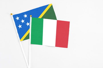 Italy and Solomon Islands stick flags on white background. High quality fabric, miniature national flag. Peaceful global concept.White floor for copy space.