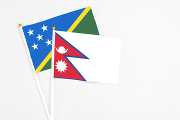 Nepal and Solomon Islands stick flags on white background. High quality fabric, miniature national flag. Peaceful global concept.White floor for copy space.