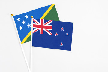 Fototapeta premium New Zealand and Solomon Islands stick flags on white background. High quality fabric, miniature national flag. Peaceful global concept.White floor for copy space.