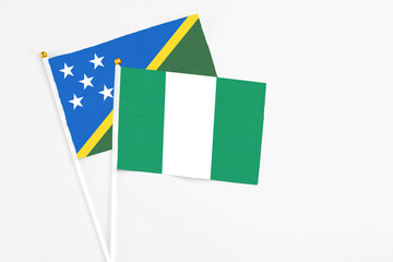 Nigeria and Solomon Islands stick flags on white background. High quality fabric, miniature national flag. Peaceful global concept.White floor for copy space.