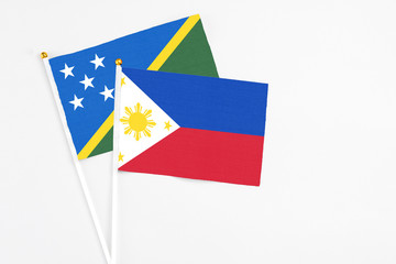 Philippines and Solomon Islands stick flags on white background. High quality fabric, miniature national flag. Peaceful global concept.White floor for copy space.