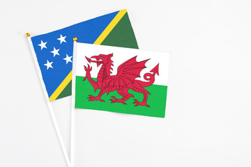 Wales and Solomon Islands stick flags on white background. High quality fabric, miniature national flag. Peaceful global concept.White floor for copy space.