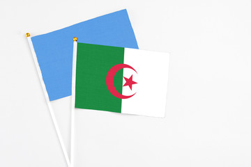 Algeria and Somalia stick flags on white background. High quality fabric, miniature national flag. Peaceful global concept.White floor for copy space.