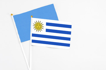 Uruguay and Somalia stick flags on white background. High quality fabric, miniature national flag. Peaceful global concept.White floor for copy space.