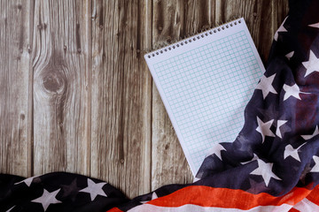 Top view of blank note paper with wood table of ruffled American flag background