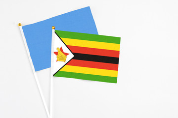 Zimbabwe and Somalia stick flags on white background. High quality fabric, miniature national flag. Peaceful global concept.White floor for copy space.