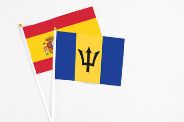 Barbados and Spain stick flags on white background. High quality fabric, miniature national flag. Peaceful global concept.White floor for copy space.
