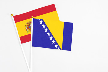 Bosnia Herzegovina and Spain stick flags on white background. High quality fabric, miniature national flag. Peaceful global concept.White floor for copy space.