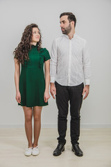 Young happy attractive couple looking into each other eyes, standing side by side, looking pleased.