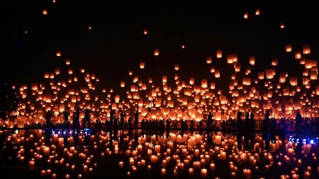 thousands of floating fire paper lanterns in the night sky with reflection in the pool at yee peng festival. Loy Krathong celebration at Sansai, Maejo university, Chiangmai, Thailand